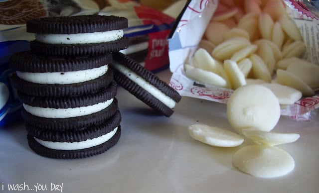 A stack of Oreos next to white chocolate melts. 