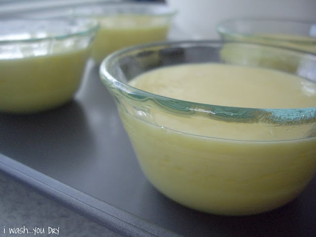 A close up of small glass dishes on a baking sheet with batter in each dish. 