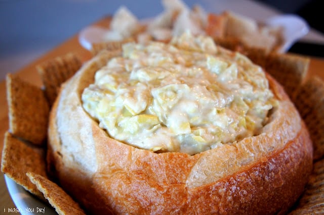 A close ups a bread bowl with a dip inside of it. 