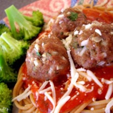 A close up of a plate of food with broccoli, meatballs and pasta.