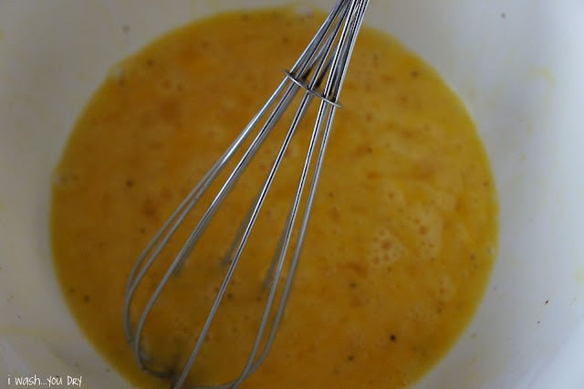 Eggs in a bowl with a wire whisk.