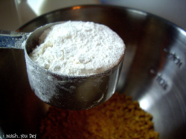 A measuring cup of flour over a mixing bowl. 