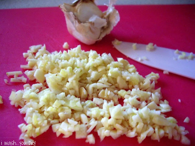 A close up of minced garlic on a cutting board. 