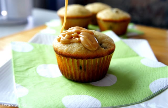A baked muffin on a napkin with a peanut butter glaze being added to the top.