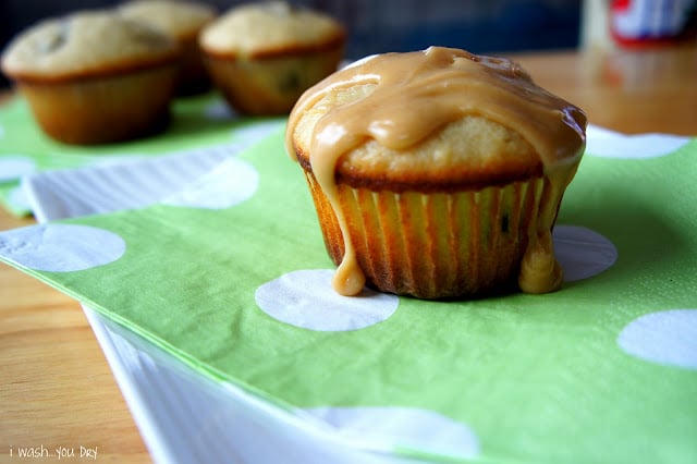 A close up of a muffin displayed on a napkin with glaze dripping from the top.