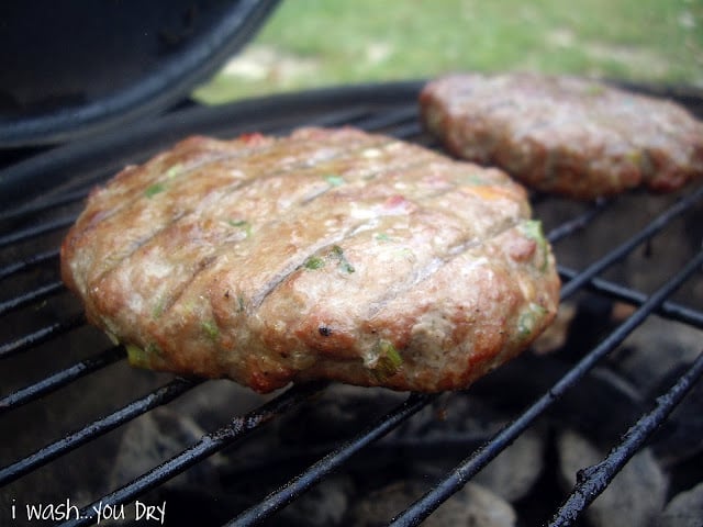 A close up of a burger cooking on a grill