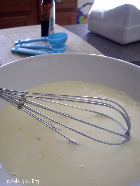 White liquid in a bowl with a wire whisk. 