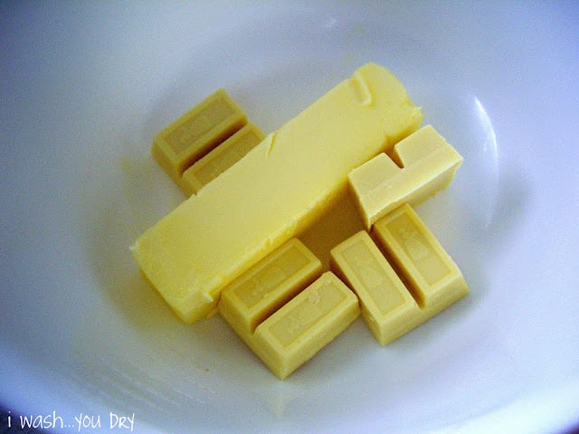 A stick of butter and four squares of white baking chocolate in a dish. 
