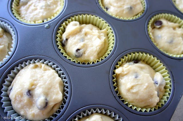 A close up of a muffin tin with batter in cupcake liners.
