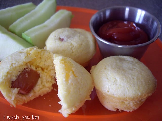 A plate displaying sliced apples, muffins and a side of ketchup. 