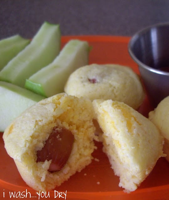 A plate displaying sliced apples, muffins and a side of ketchup. 