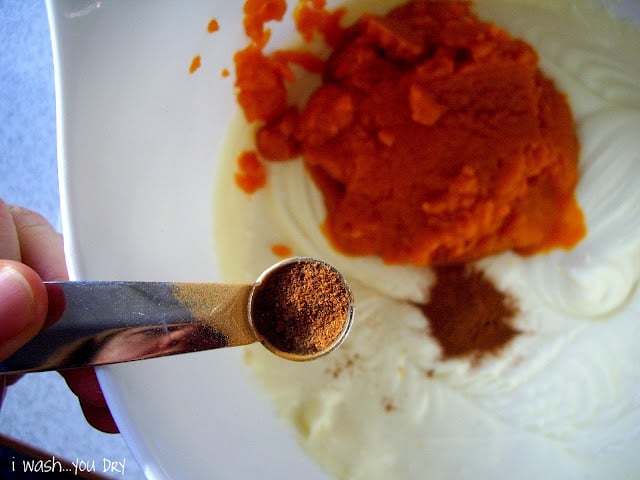 A measuring spoon of nutmeg above a bowl of batter. 