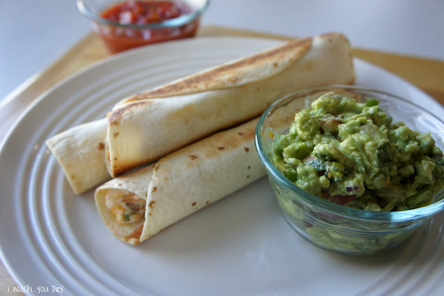 Three Flautas on a plate next to a small bowl of guacamole.