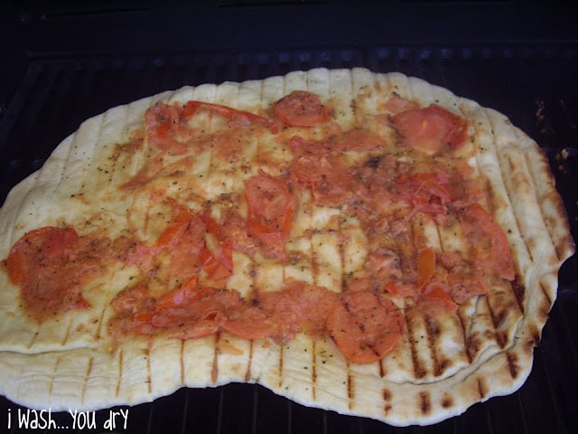 Smashed grilled tomatoes on top of a grilled pizza crust. 