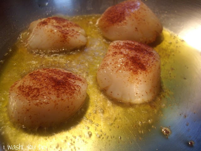 Seasoned scallops frying in a pan.