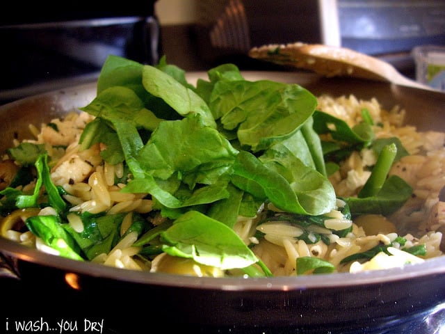A pan of food topped with spinach. 