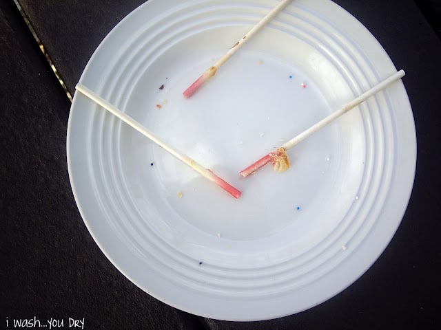 An empty plate with three used sucker sticks left on it.