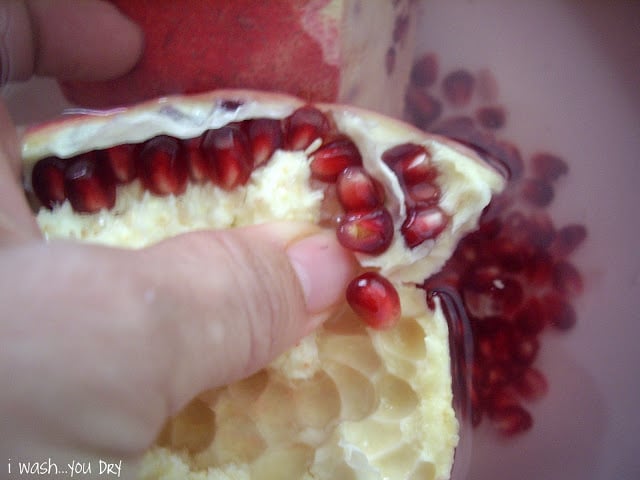 A thumb demonstrating how to remove the pomegranate seed