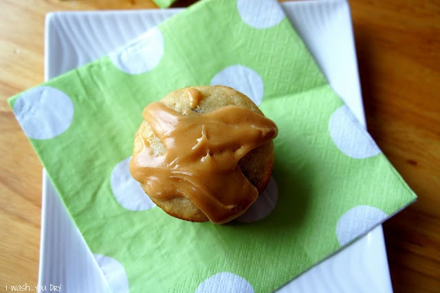 A muffin topped with a glaze sitting on top of a green polka dot napkin.