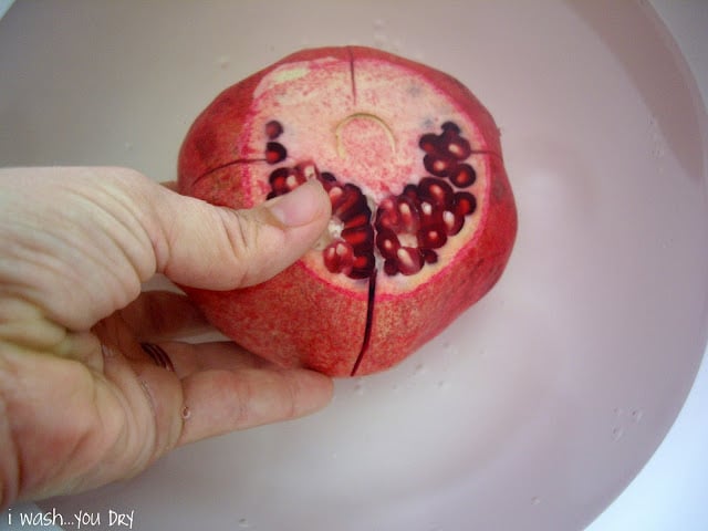 A hand removing a slice of the pomegranate.