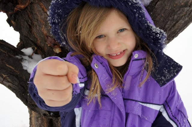 A little girl holding a fist out. 