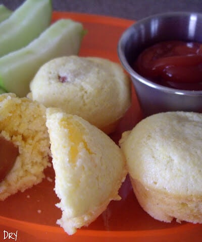 A plate displaying sliced apples, muffins and a side of ketchup.