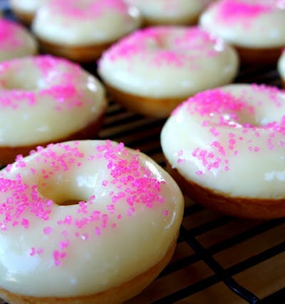 Pink sprinkled glazed donuts on a cooling rack