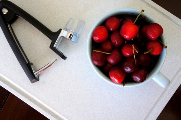 A close up of a bowl of cherries ready to be pitted