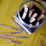 A look down on popsicle sticks with jobs on them next to a jar with stick poking out of it