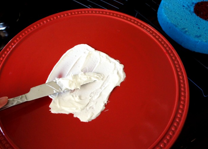 White frosting spread on a small area of a red cake tray