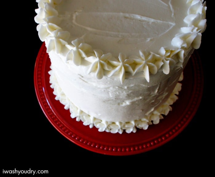 A close up of a decorated cake on a plate, with white Icing and red plate