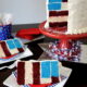 Slices of 5 layer 4th of July themed birthday cake on plates next to the full cake on a cake stand.