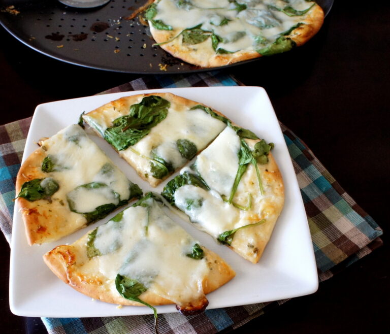 A sliced baked white pita pizza displayed on a plate 