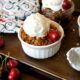 Cherry Crisp in a small dessert bowl topped with a scoop of ice cream with a fresh cherry on top
