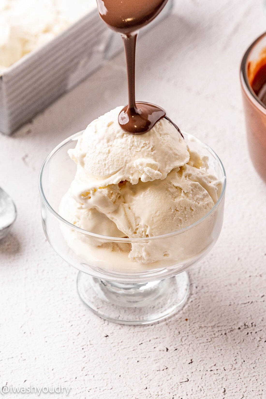 Pouring Magic shell over glass dish of vanilla ice cream. 