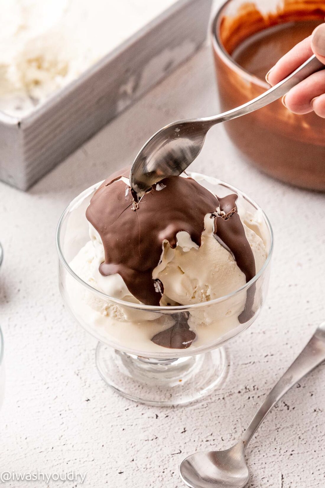 Bowl of vanilla ice cream with chocolate shell on top. 