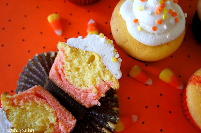 A candy corn styled cupcake sliced in half, displayed next to other candy corn cupcakes