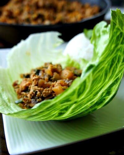 Chinese chicken mix laying in a leaf of lettuce displayed on a plate