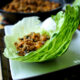 Chinese chicken mix laying in a leaf of lettuce displayed on a plate