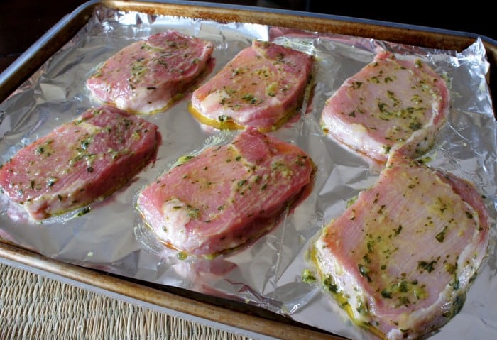 A pan of raw meat topped with a basil and garlic herb