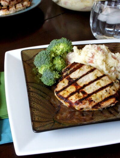 A plate with a grilled pork chop and sides of mashed potatoes and broccoli