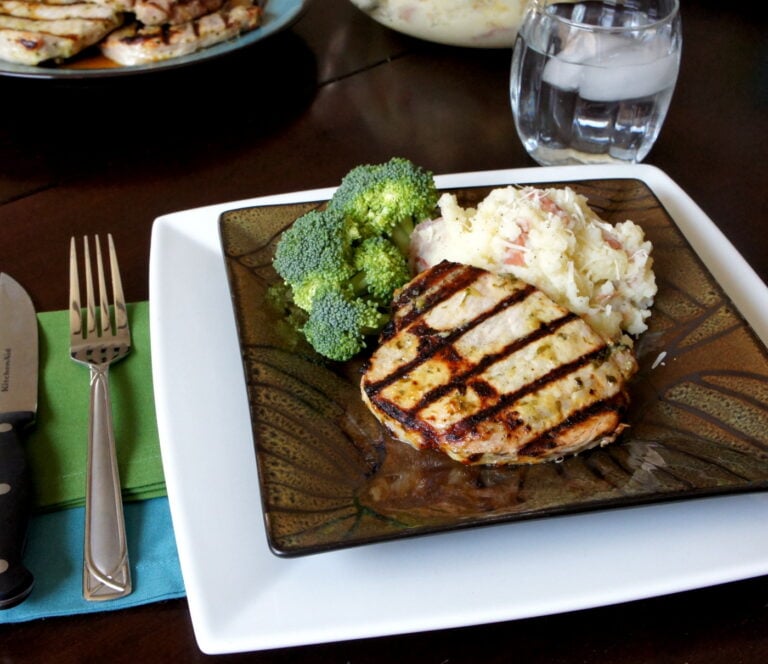 A plate with a grilled pork chop and sides of mashed potatoes and broccoli