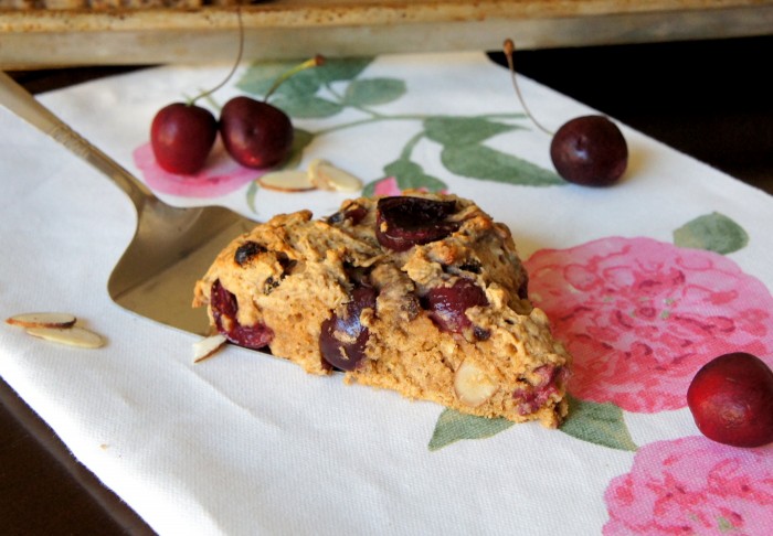 A slice of a cherry scone being placed on a napkin