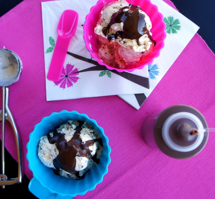 Two bowls of ice cream topped with chocolate sauce next to a bottle of homemade chocolate sauce