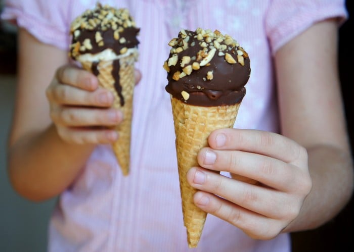 A child a chocolate dipped ice cream cone in both of their hands