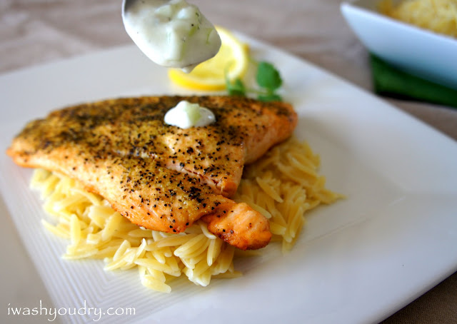 A spoon dripping Tzatziki Sauce on a Greek Salmon Fillet on a bed of noodles.