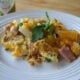 A plate displaying food; with ham, potatoes, eggs and cheese.