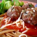Meatballs on top of spaghetti noodles and a red sauce with side of broccoli.