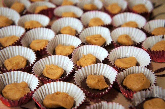Mini muffin tins with a layer of melted chocolate on the bottom of each topped with a dollop of cookie butter 