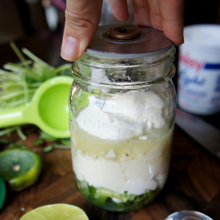Salad dressing ingredients in a mason jar with blender blades on top